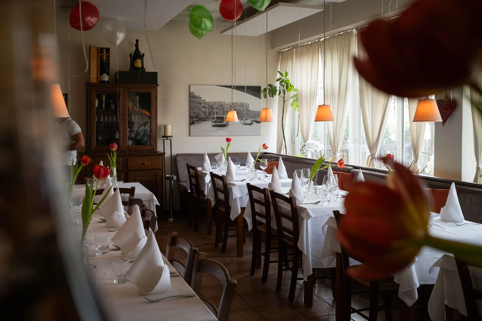 Unser Gastraum — warm gedeckt mit Tulpen und Venedig-Motiv